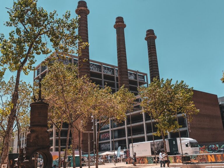 a large building with three tall towers next to a tree